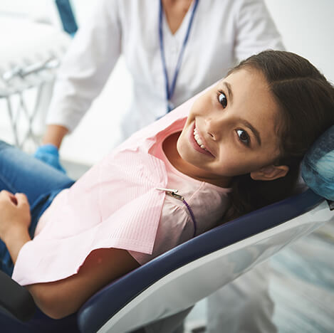smiling young girl sitting in a dental chair