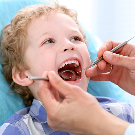 young boy having his teeth examined by a dentist