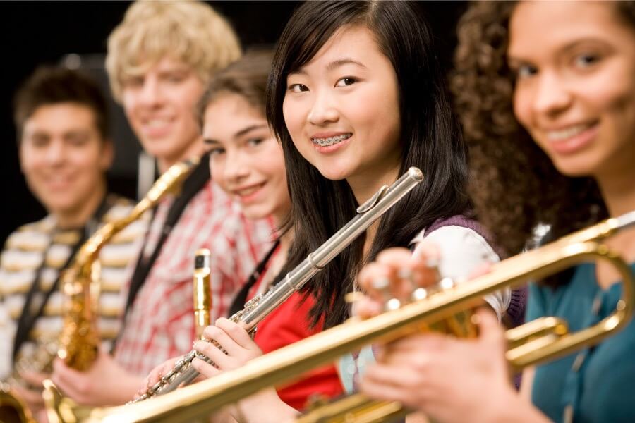 High school girl with braces smiles while holding her wind instrument in the orchestra