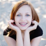 Red head teenager smiles with her braces that she keeps clean