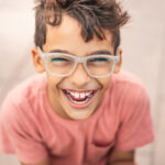 Brunette boy in glasses smiles with healthy teeth between visits to the dentist in Laredo, TX